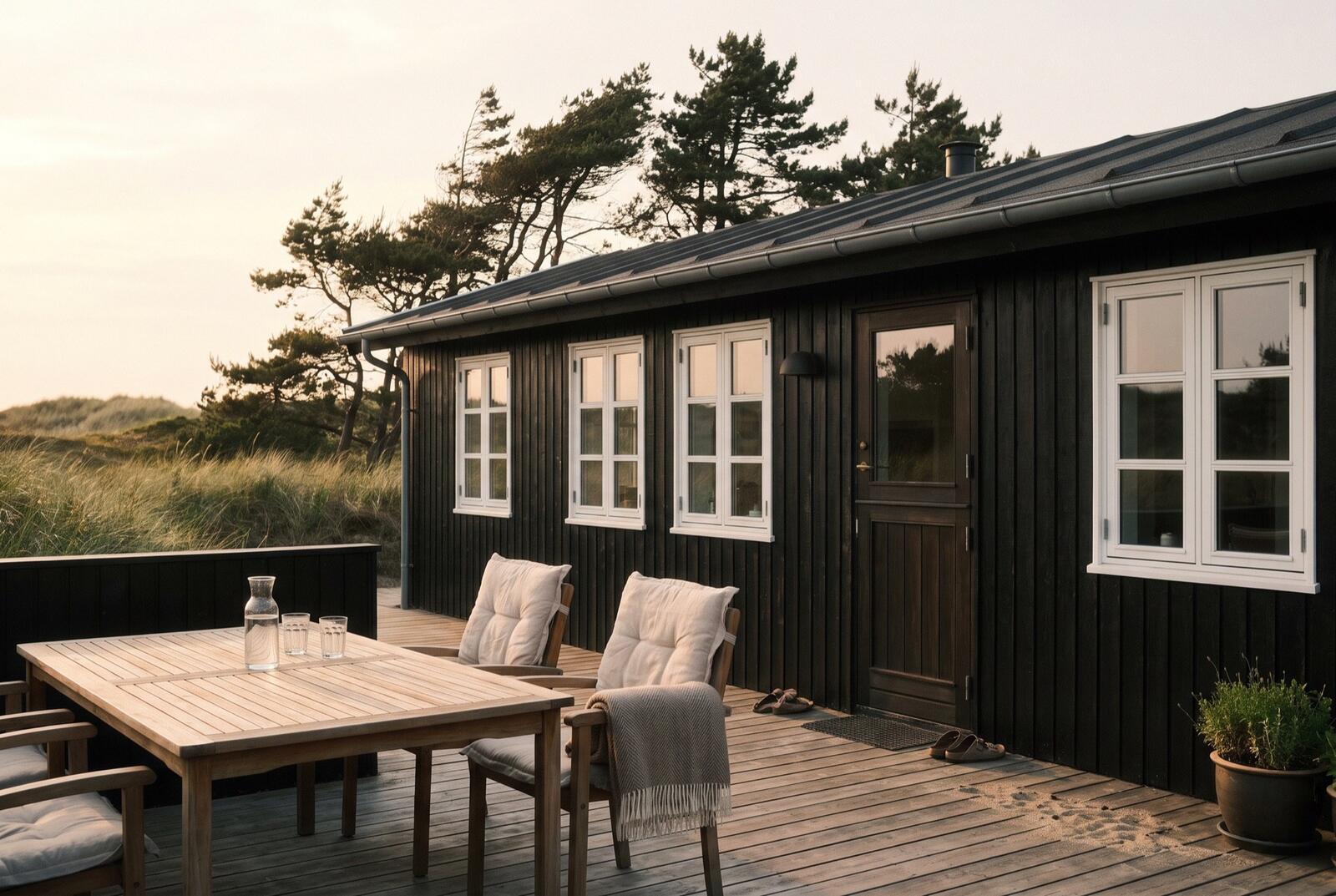 Træterrasse ved et sommerhus mellem klitter og fyrretræer