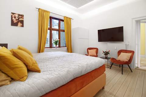Elegant and spacious bedroom with a luxurious king-size bed, refined décor, generous storage, and a large flat-screen TV. A calm, high-end retreat designed for comfort and relaxation in central Aarhus.