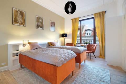 Spacious and serene bedroom featuring a luxurious king-size bed that can be separated into two single beds upon request, elegant décor, and generous storage. The perfect retreat to unwind after a day in the heart of Aarhus.