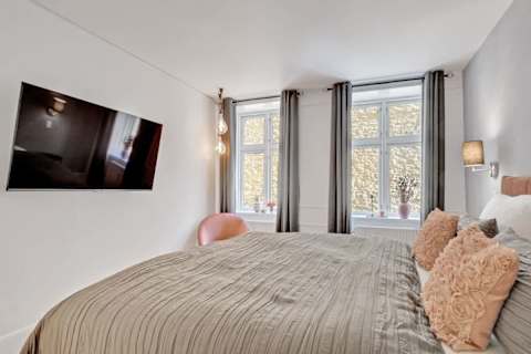 Calm bedroom with a queen-size bed and TV, perfect for relaxing after a day in the city. A peaceful and cozy space designed for a great night’s sleep.