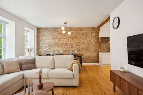 Bright living area and open kitchen with original Copenhagen brick wall from the 1700s