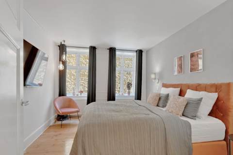 Calm bedroom with a queen-size bed and TV, perfect for relaxing after a day in the city. A peaceful and cozy space designed for a great night’s sleep.