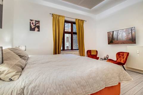 Elegant and spacious bedroom with a luxurious king-size bed, refined décor, generous storage, and a large flat-screen TV. A calm, high-end retreat designed for comfort and relaxation in central Aarhus.