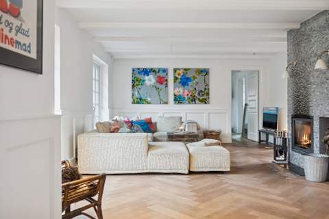 A bright and inviting living room with generous seating, soft textures and natural light — designed for relaxed afternoons, quiet evenings and shared moments together.