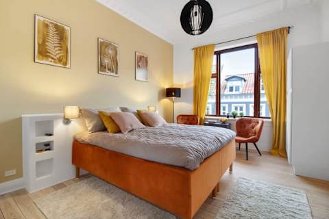Spacious and serene bedroom featuring a luxurious king-size bed that can be separated into two single beds upon request, elegant décor, and generous storage. The perfect retreat to unwind after a day in the heart of Aarhus.