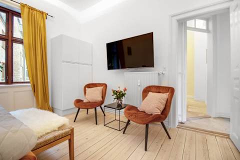 Elegant and spacious bedroom with a luxurious king-size bed, refined décor, generous storage, and a large flat-screen TV. A calm, high-end retreat designed for comfort and relaxation in central Aarhus.