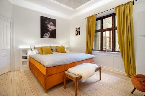 Elegant and spacious bedroom with a luxurious king-size bed, refined décor, generous storage, and a large flat-screen TV. A calm, high-end retreat designed for comfort and relaxation in central Aarhus.