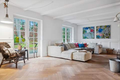 A bright and inviting living room with generous seating, soft textures and natural light — designed for relaxed afternoons, quiet evenings and shared moments together.