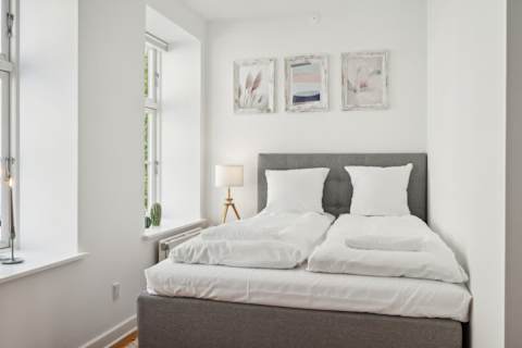 Bright and Calm bedroom with a queen-size bed and TV, perfect for relaxing after a day in the city. A peaceful and cozy space designed for a great night’s sleep.